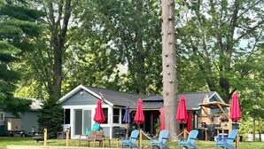 A lakeside cabin with a dock, outdoor seating with umbrellas, and a small kitchen area.