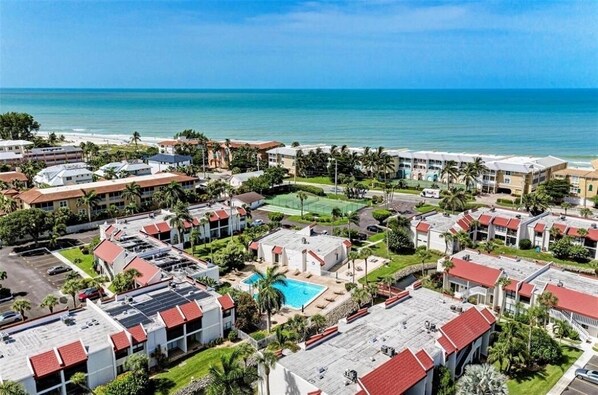 A coastal hotel with multiple buildings, a swimming pool, and a view of the ocean.