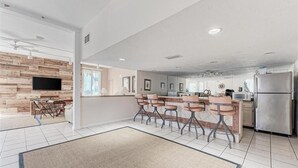 Una cocina moderna con una isla central, electrodomésticos de acero inoxidable y un televisor de pantalla plana montado en una pared de madera.