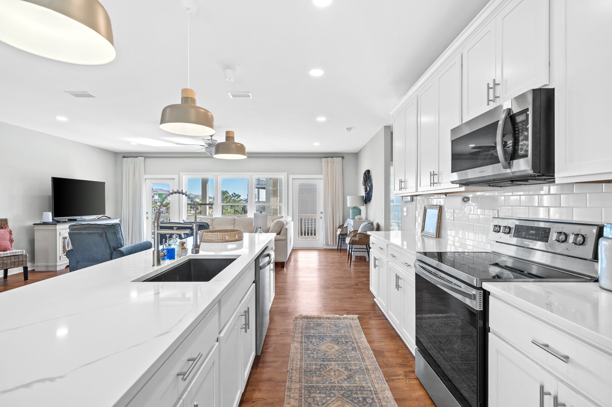 A modern kitchen with white cabinetry, stainless steel appliances, and a large island.