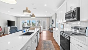 Une cuisine moderne avec des meubles blancs, des appareils en acier inoxydable et un grand îlot central.