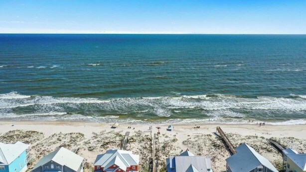 Une vue sur la plage, avec des maisons au premier plan et l’océan en arrière-plan.