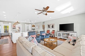 Un salon moderne avec un canapé, des fauteuils, une table basse et un téléviseur.