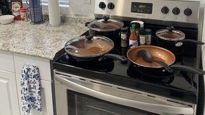 Une cuisine équipée d’une cuisinière, de casseroles et d’un panneau indiquant : « CAFÉ FRAÎCHEMENT PREPARÉ TOUS LES JOURS ».