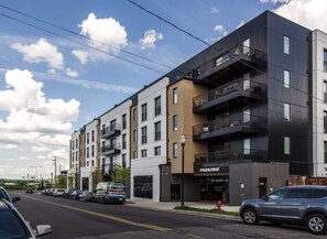 A multi-story building with a parking garage labeled "PARKING" and a storefront with a sign.