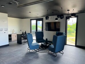 Una sala de estar moderna con comedor, ventanas amplias y una cocina al fondo.