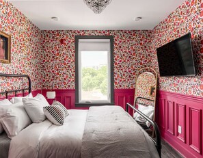 Ein Schlafzimmer mit Bett, Fenster und Fernseher.