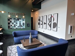A modern lounge area with blue sofas, a coffee table, and abstract wall art.