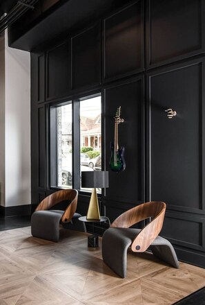 A modern interior with two wooden chairs, a lamp, and guitars on a wall.