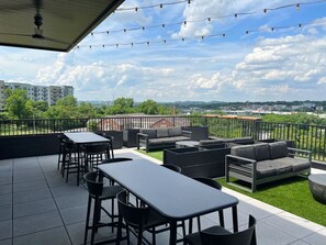 Eine Außenpatio mit Sitzgelegenheiten und Tischen, Blick auf die Stadt und einem klaren Himmel.