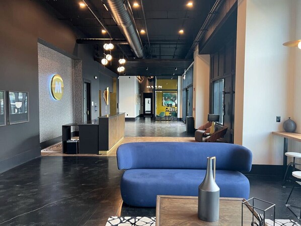 A modern lobby with a reception desk, a blue sofa, and a vase on a table.