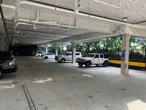 An underground parking garage with concrete pillars, marked parking spaces, and a few vehicles.