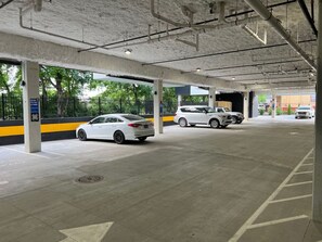 A parking garage with concrete pillars, marked parking spaces, and a few cars parked.