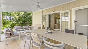 A spacious patio with a long dining table, white chairs, and a ceiling fan. - Peaceful Family Villa in Sunrise Beach (Sunrise Beach)