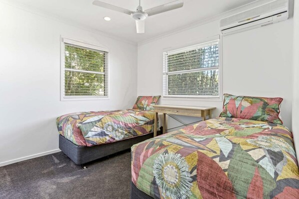 Un dormitorio con dos camas, un escritorio y un ventilador de techo.