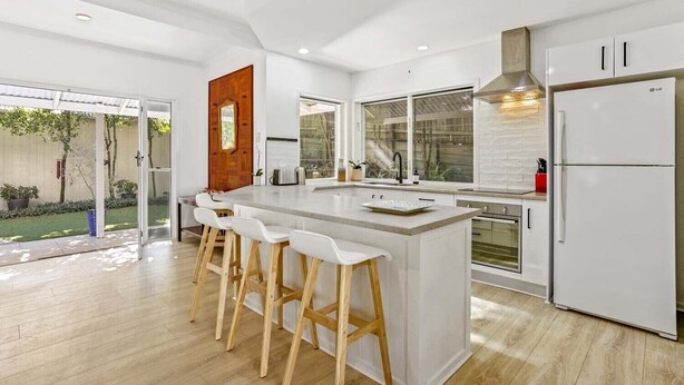A modern kitchen with a large island, bar stools, a built-in oven, and a refrigerator. - Peaceful Family Villa in Sunrise Beach (Sunrise Beach)