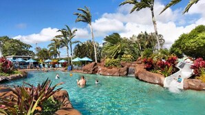 A clear pool with palm trees, a waterfall, and lounge chairs. - Luxury Ground Floor Condo Just 50 Yards From The Beach! (Koloa)