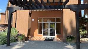 A building entrance with a glass door, a number '4300' sign, and a wooden pergola structure. - Large Lakefront 3 Bed Condo With Gorgeous Osoyoos Lake and Mountain Views (Osoyoos)