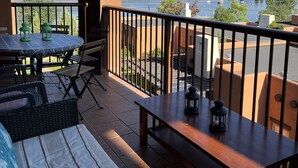 A balcony with a view of a lake and mountains, furnished with a table, chairs, and a bench. - Large Lakefront 3 Bed Condo With Gorgeous Osoyoos Lake and Mountain Views (Osoyoos)