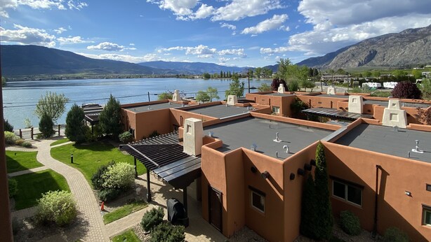 A building with a flat roof, a covered outdoor area, and a view of a lake and mountains. - Large Lakefront 3 Bed Condo With Gorgeous Osoyoos Lake and Mountain Views (Osoyoos)