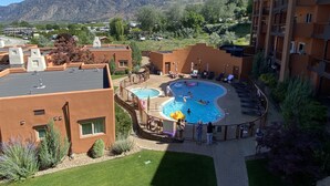 A pool area with a view of mountains, surrounded by buildings with a modern architectural style. - Large Lakefront 3 Bed Condo With Gorgeous Osoyoos Lake and Mountain Views (Osoyoos)