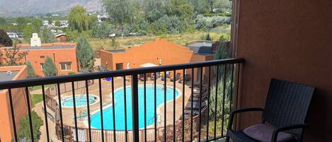 A balcony with a view of a swimming pool and mountains.