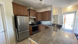 A kitchen with granite countertops, stainless steel appliances, wooden cabinets, and a large island. - Large Lakefront 3 Bed Condo With Gorgeous Osoyoos Lake and Mountain Views (Osoyoos)
