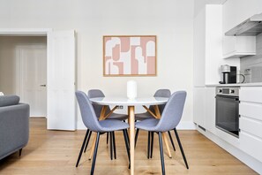 A modern kitchen with white cabinets, a built-in oven, and a coffee machine.