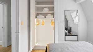 A bedroom with a large bed, a walk-in closet with shelves and hanging space, and a mirror on the wall. - Open plan Waterloo, 2BR, New build, terrace, by Blueground (London)