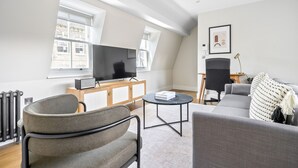 A modern living room with a flat-screen TV, a sofa, a chair, and a coffee table. - Open plan Waterloo, 2BR, New build, terrace, by Blueground (London)