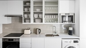 A modern kitchen with white cabinets, a built-in oven, a coffee maker, and a microwave. - Open plan Waterloo, 2BR, New build, terrace, by Blueground (London)
