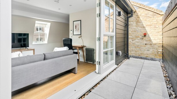 A modern living room with a grey sofa, a TV, and a desk. - Open plan Waterloo, 2BR, New build, terrace, by Blueground (London)