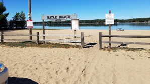 Un cartel de playa con la leyenda 'Bayak Beach' y 'Privado', junto a un anuncio de la Asociación de Bayak Beach que agradece a los visitantes por retirar basura y colillas.