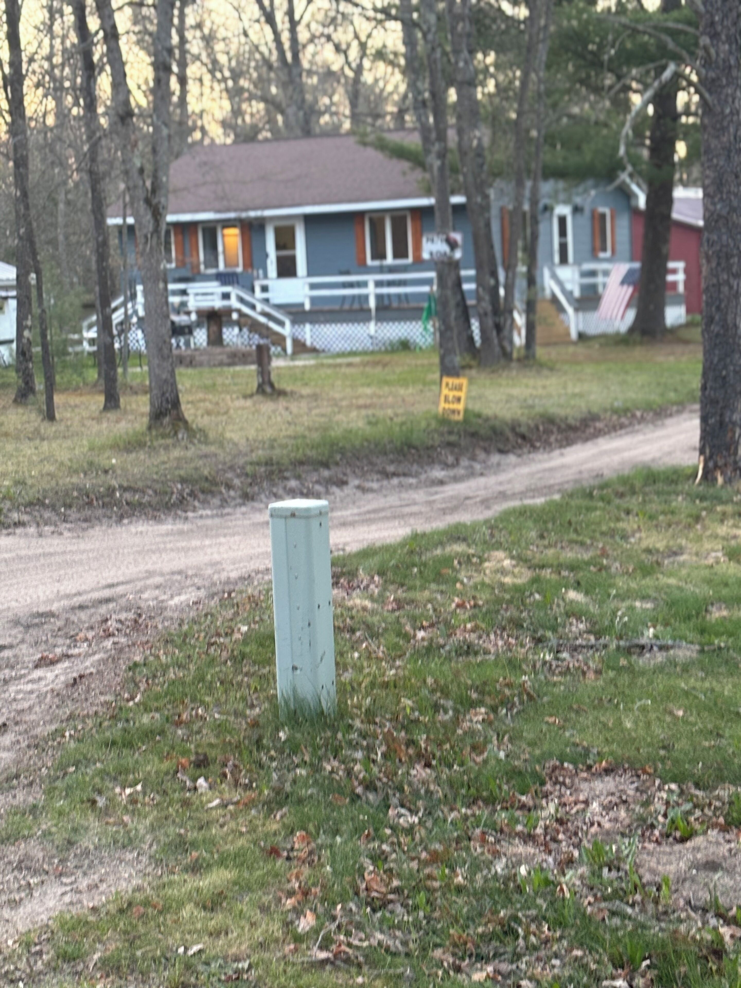 Un camino rural con una caja de servicios de madera y un cartel que indica camino privado.