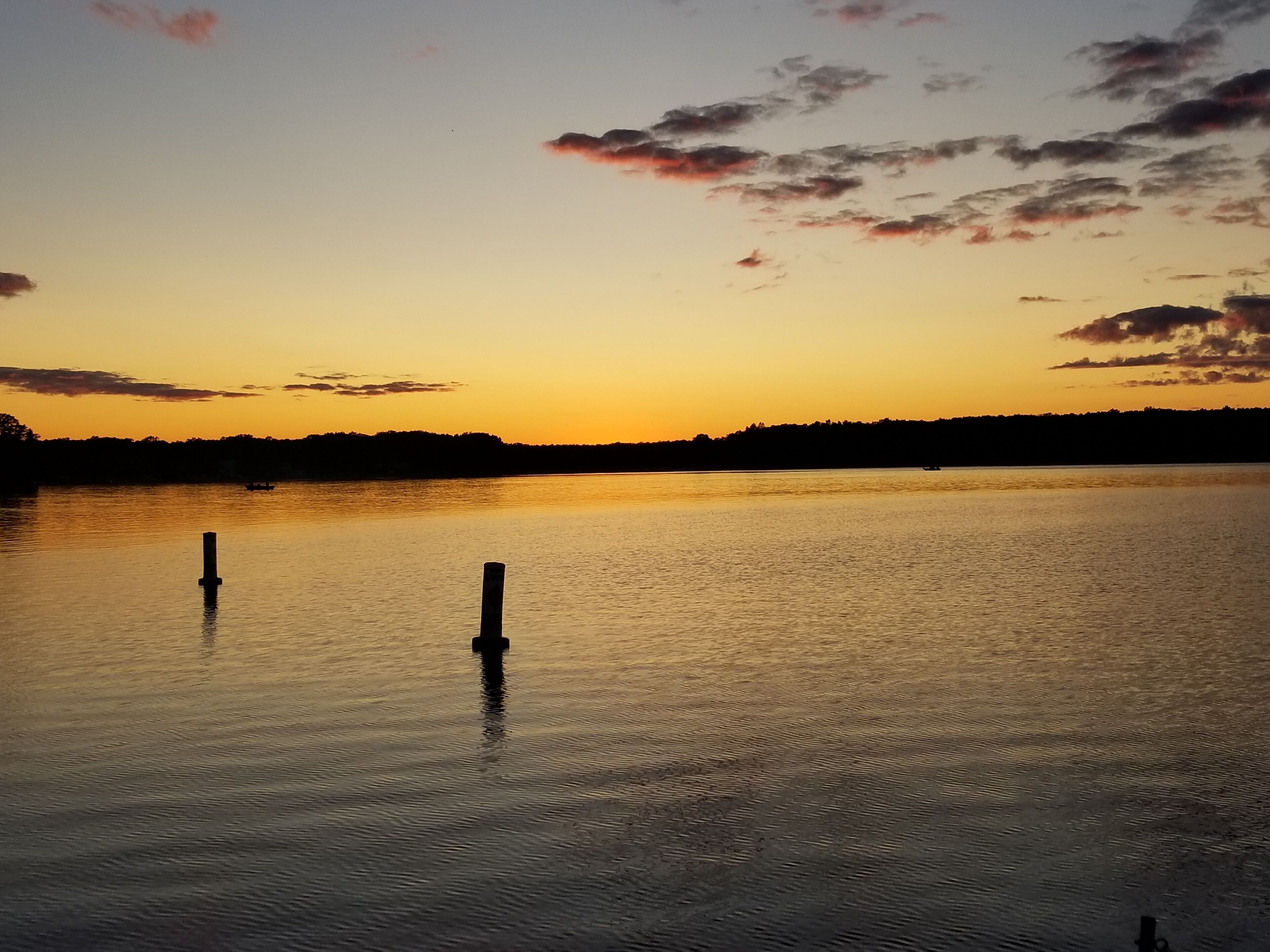Un lac paisible au coucher du soleil, sous un ciel dégagé.