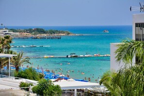 A coastal view with a beach, boats, and a pier.