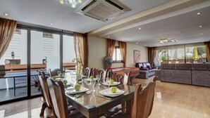 A dining area with a table set for four, a sofa, and a pool table in the background.