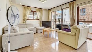 A modern living room with a sofa set, a coffee table, a TV, and a standing fan. - Fabulous Sea view Villa with big luxury Jacuzzi in Protaras, Protaras Villa 1676 (Protaras)