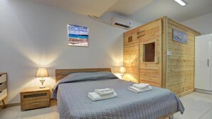 A bedroom with a bed, bedside lamps, a wooden cabin structure, and a wall-mounted air conditioner. - Fabulous Sea view Villa with big luxury Jacuzzi in Protaras, Protaras Villa 1676 (Protaras)
