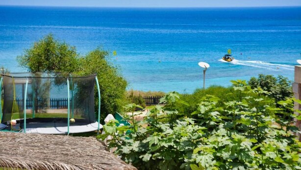 A trampoline in a backyard with a view of the ocean and a jet ski in the distance. - Fabulous Sea view Villa with big luxury Jacuzzi in Protaras, Protaras Villa 1676 (Protaras)