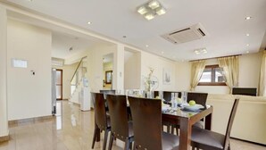 A spacious dining area with a high table and chairs, a kitchen area with a refrigerator and stove, and a living area with a sofa and a TV. - Fabulous Sea view Villa with big luxury Jacuzzi in Protaras, Protaras Villa 1676 (Protaras)