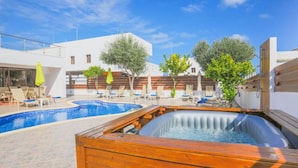 Uma área de piscina com hidromassagem, espreguiçadeiras e um deck de madeira.