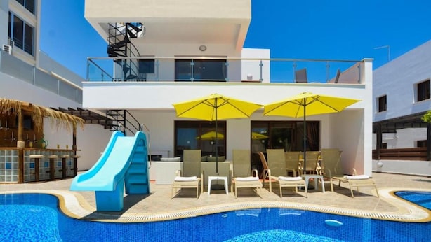 Um hotel moderno com piscina, espreguiçadeiras e guarda-sóis.