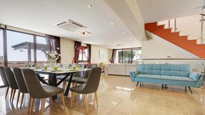 Uma sala de estar moderna com área de jantar, um sofá azul e uma escada.