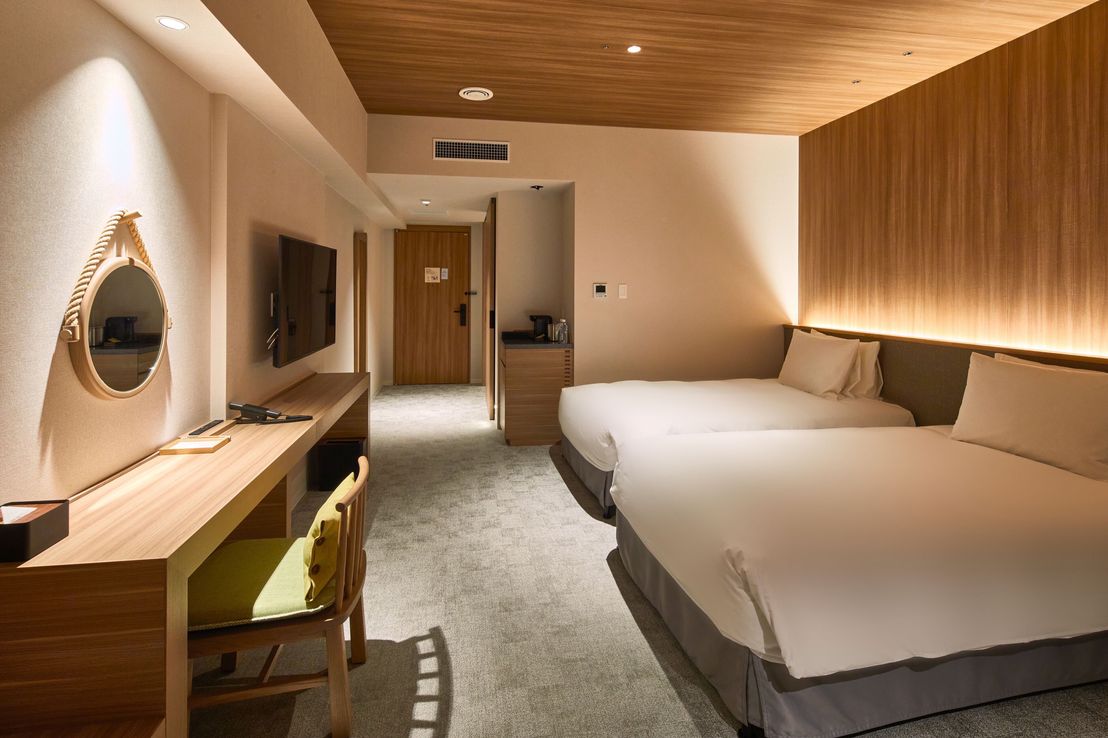 Une chambre d’hôtel avec un bureau en bois, un lit avec une literie blanche et un téléviseur fixé au mur.