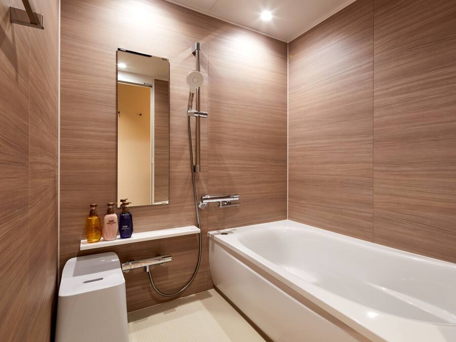 Un baño moderno con bañera, ducha y tocador con artículos de aseo.