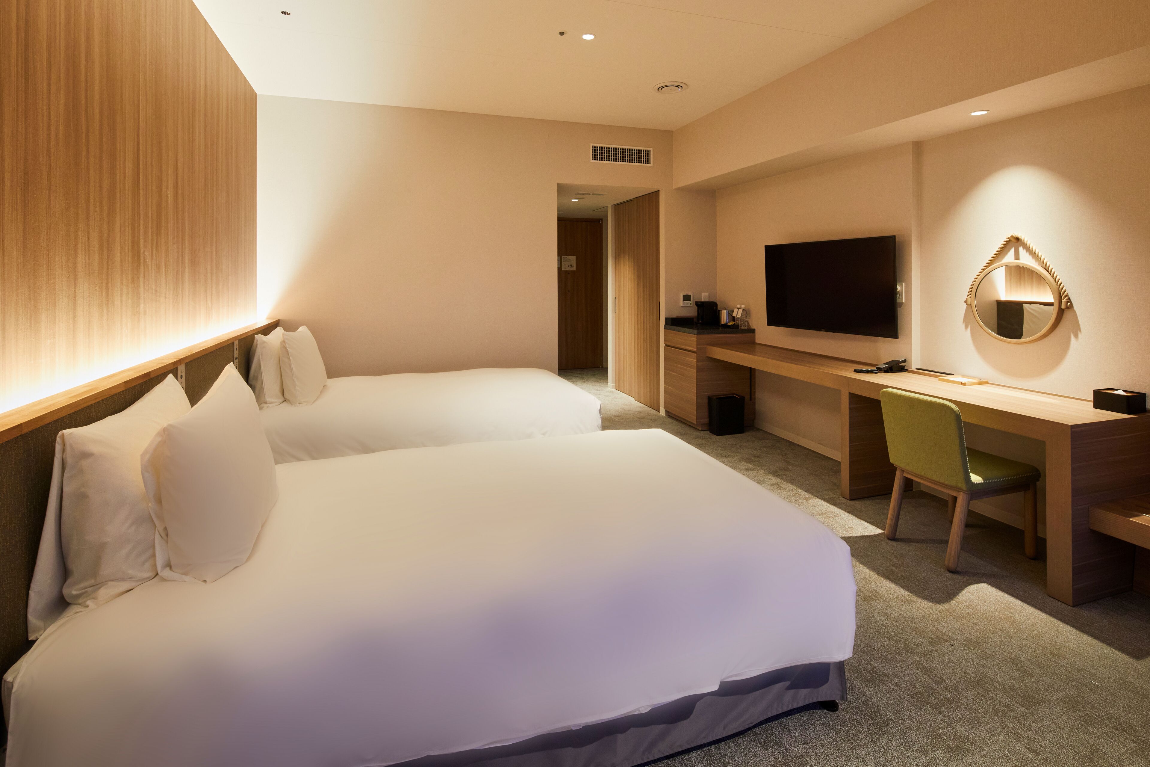 Une chambre d’hôtel avec deux lits, un bureau, une chaise, une télévision et un miroir.