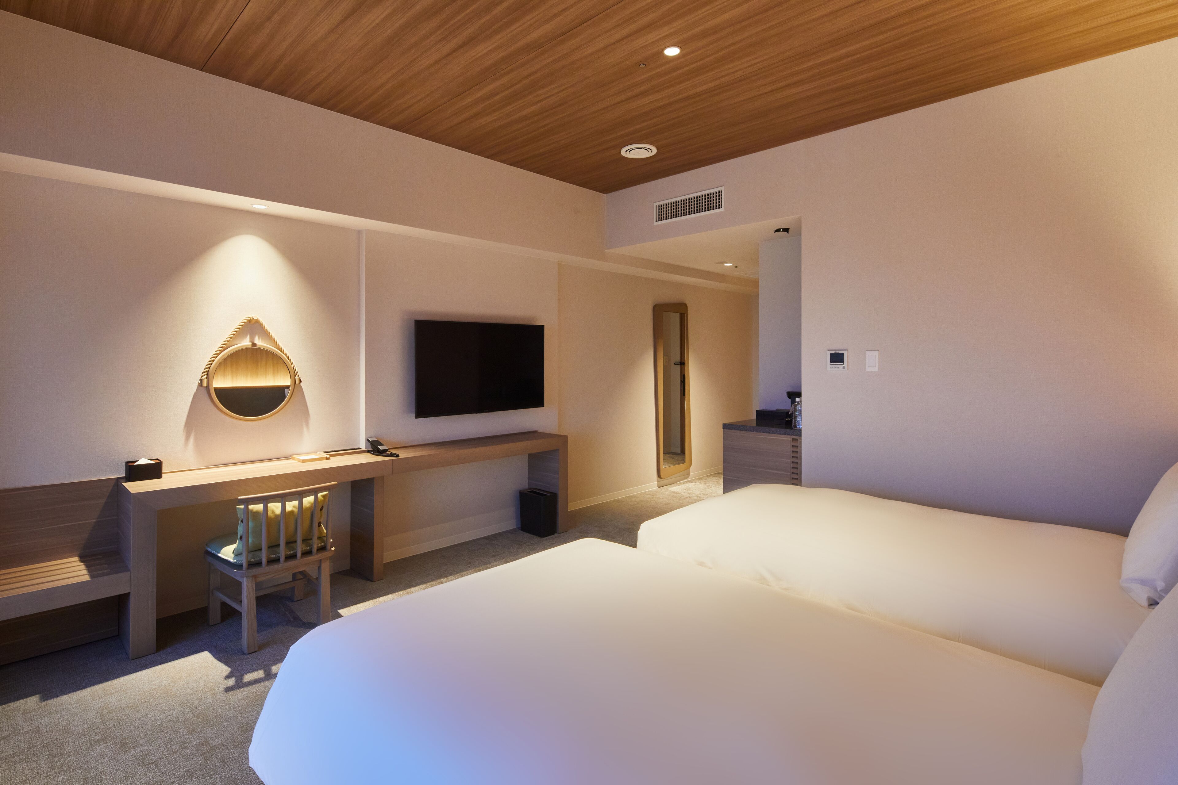 Una habitación de hotel moderna con techo de madera, televisor de pantalla plana en la pared, escritorio con silla y una cama grande.