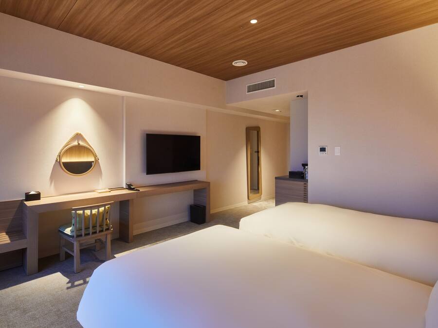 Una habitación de hotel moderna con techo de madera, televisor de pantalla plana en la pared, escritorio con silla y una cama grande.