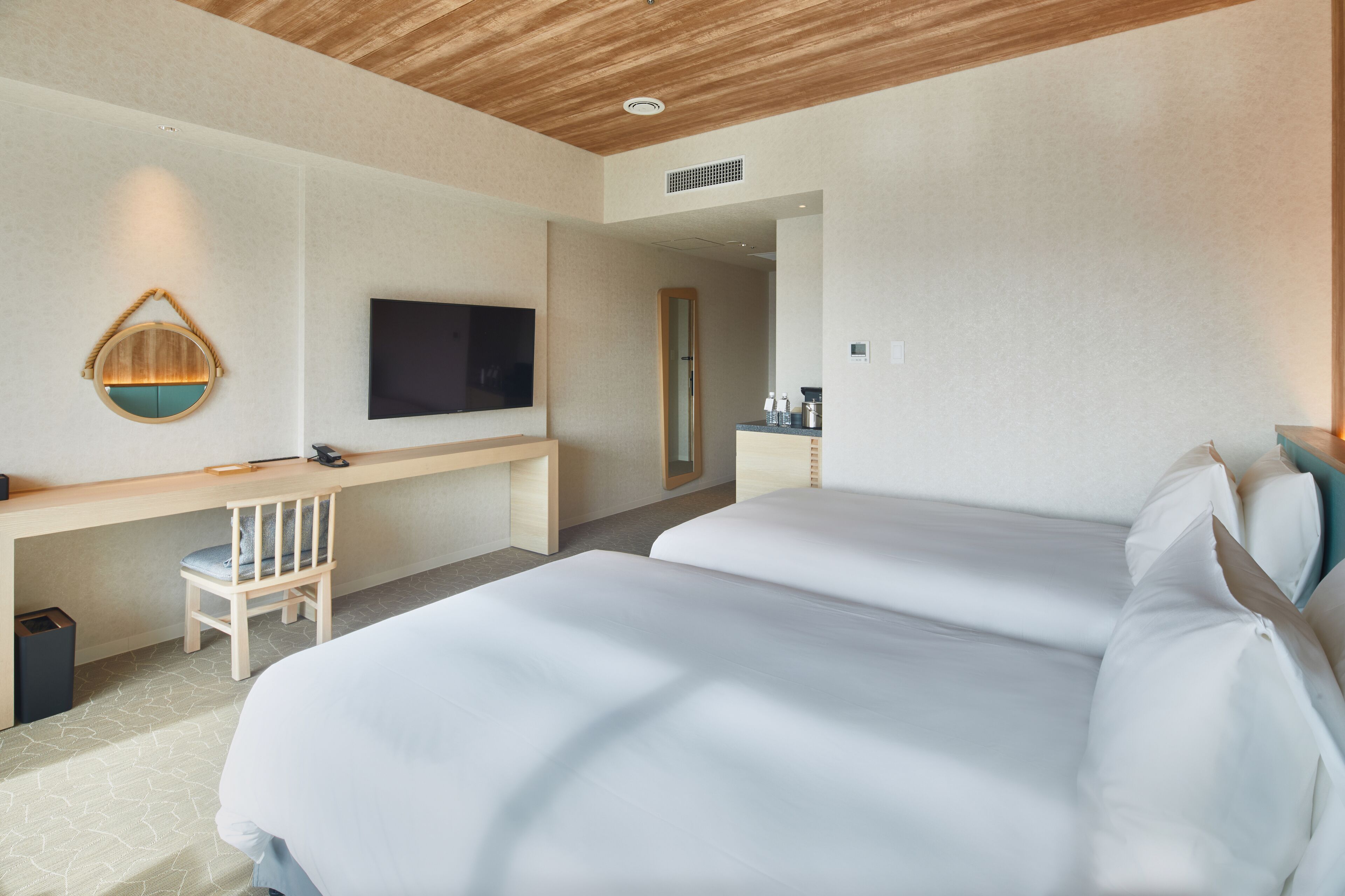 Une chambre d’hôtel avec deux lits, un bureau, une chaise, une télévision et un miroir.